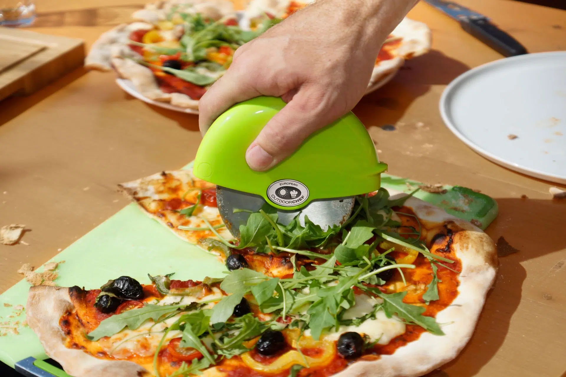 Outdoorchef Pizzaschneider beim Schneiden einer Pizza